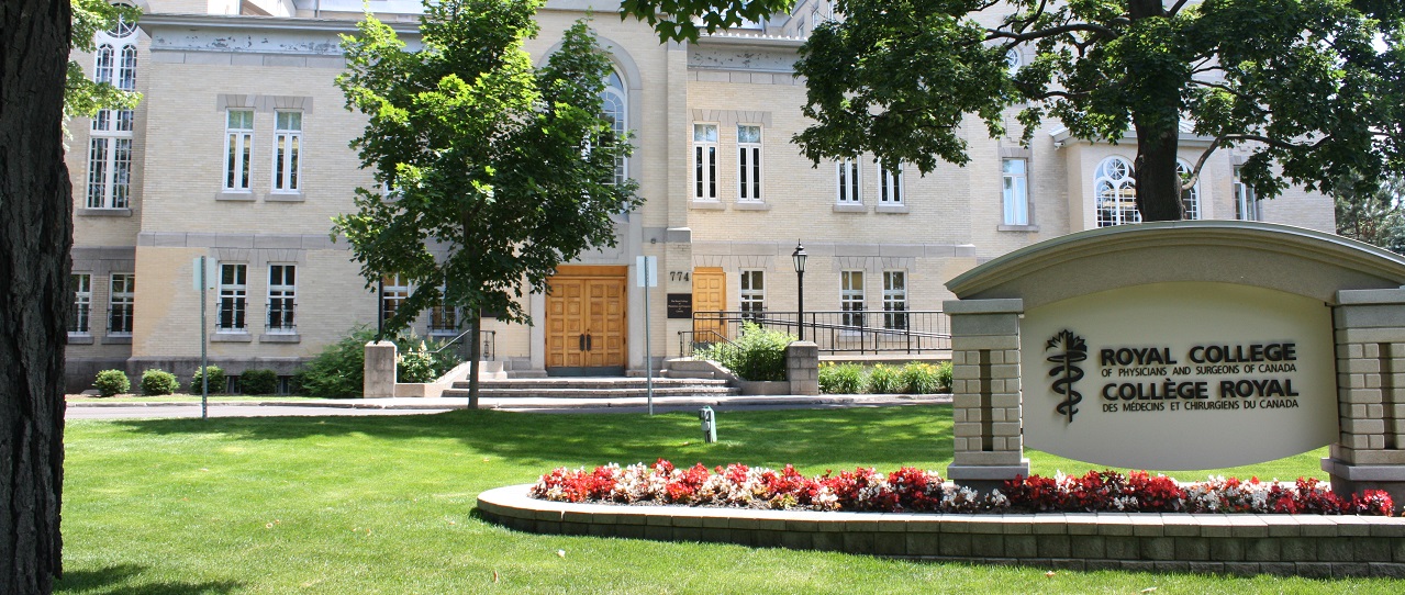 The front of the Royal College of Physicians and Surgeons campus, including large wooden doors and a sign surrounded by flowers.